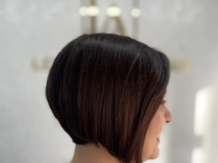 Corte bob assimétrico em cabelo castanho escuro, visto de perfil
