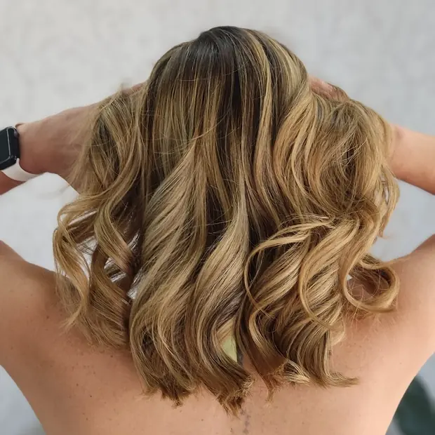 Corte médio ondulado com mechas douradas